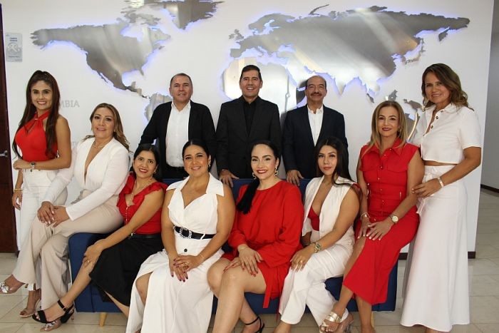 Equipo de ANDAR Inmobiliaria posando en su oficina frente a un mapa mundial, expertos en ventas, arriendos y avalúos de propiedades en Ibagué, Bogotá y otras ciudades de Colombia.